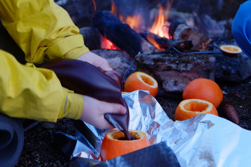 Flytende sjokolade fylles i appelsinene som legges i aluminiumsfolie på bålet